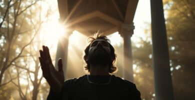 Eine Untersichtaufnahme eines betenden Mannes, der mit erhobener Hand zum Himmel blickt. Im Hintergrund sind einige Bäume und intensives Sonnenlicht zu sehen.